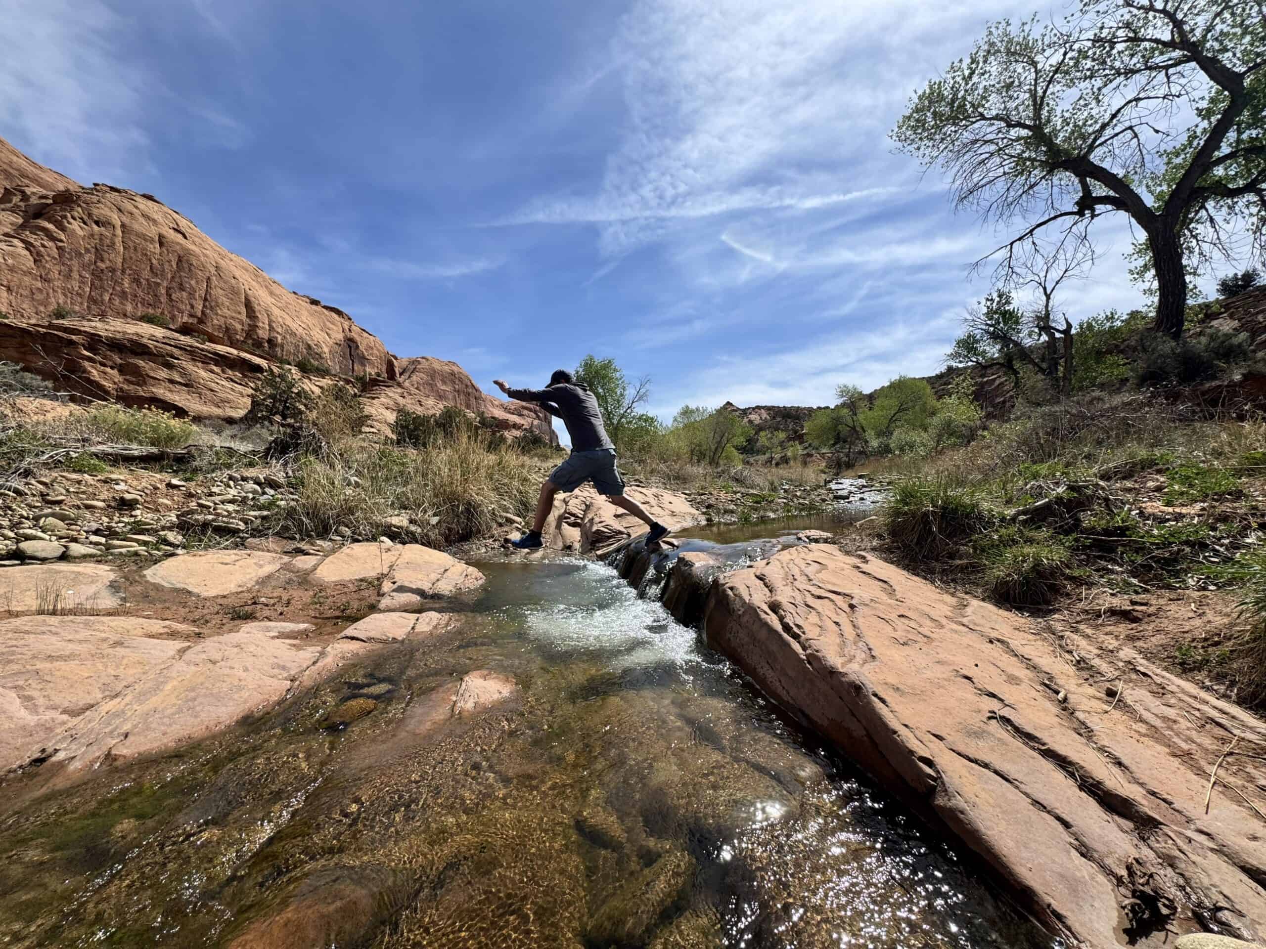 A man leaping across a desert creek