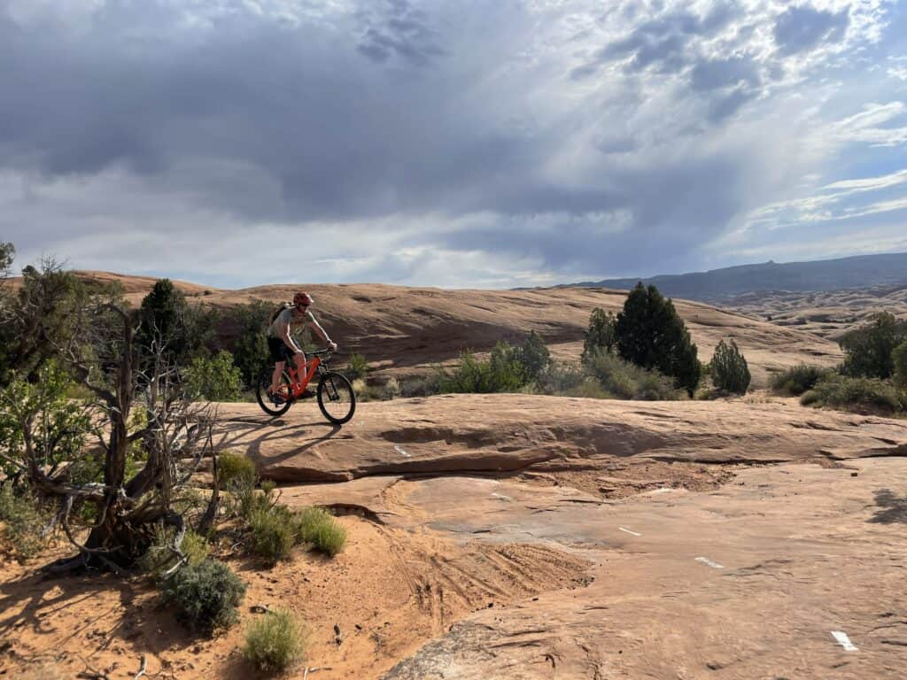 - A father navigating slickrock in Moab, symbolizing the reset and recalibration at the heart of PathForgeXP retreats.

