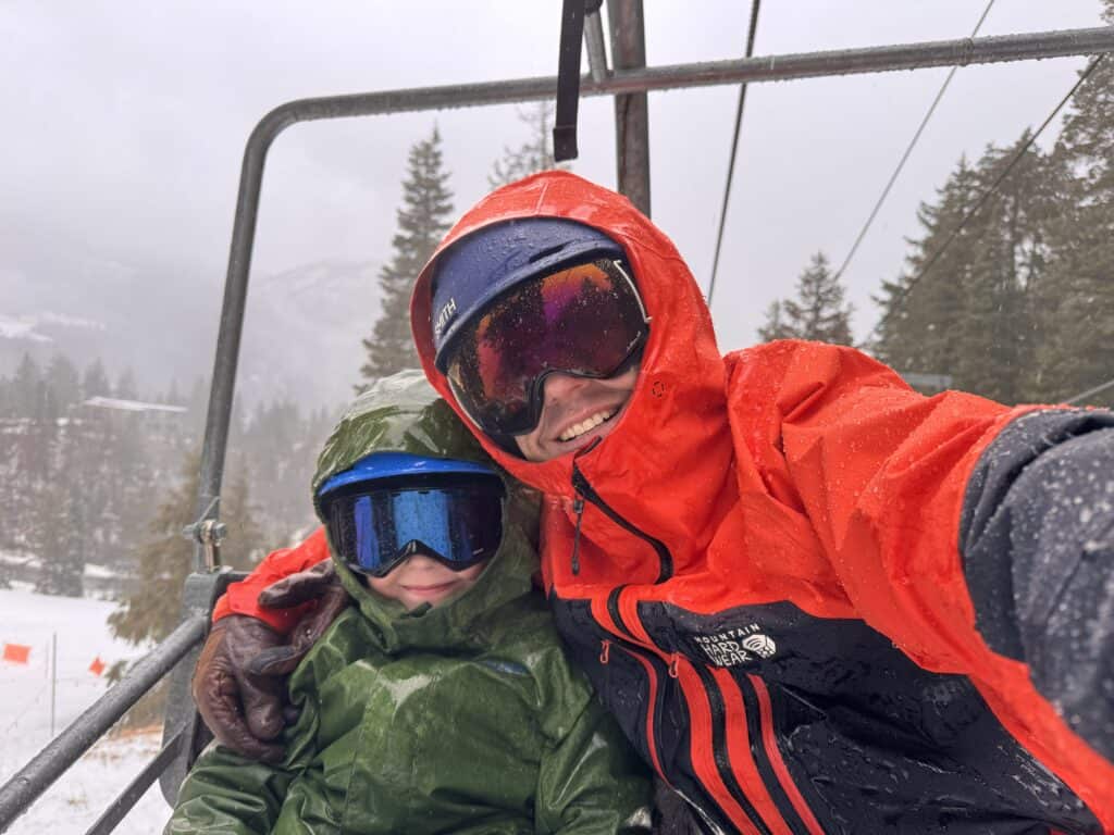 A father and son ride a ski lift together, sharing time outdoors and building connection through a powerful winter experience.